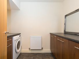 A laundry room with a washing machine and cabinets at Whitewater Seaview in Newquay