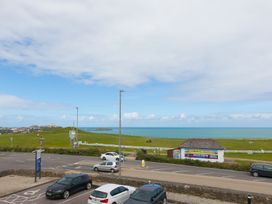 A view of the sea and grassland with parked cars at Whitewater Seaview in Newquay