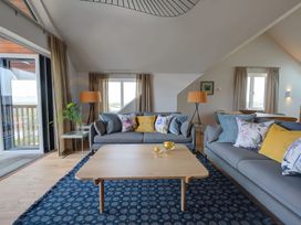 A living room with two gray sofas a wooden coffee table and blue patterned rug at Villa 1 in Mullion