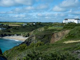 A coastal landscape with cliffs a sandy beach and buildings on a hillside at Villa 1 in Mullion