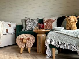 A living room with a couch, pillows, candle, and a wooden table at Willow in Llangurig near Llanidloes