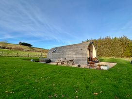 A wooden pod with patio furniture and a hot tub at Willow in Llangurig near Llanidloes