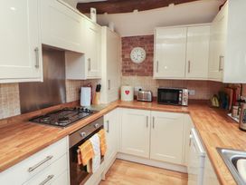 A kitchen with stove, microwave, and cabinets at River Cottage in Eamont Bridge