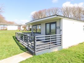 A single-story cottage with a fenced porch and outdoor seating on a grassy area at Cassia in Kilkhampton