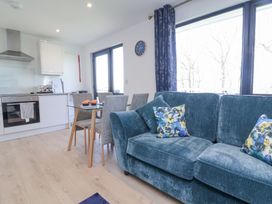 An open-plan living room and kitchen with a blue sofa and dining table with chairs at Cassia Kilkhampton