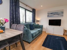 A living room with a green sofa and a TV at Cassia in Kilkhampton