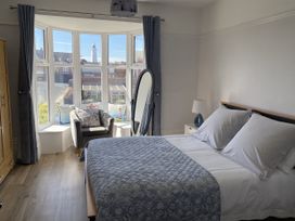 A bedroom with a bed and a chair near windows at 46 The Promenade in Withernsea