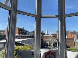 A conservatory with a view of buildings and a lighthouse at 46 The Promenade in Withernsea