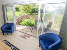 A room with two blue armchairs facing glass sliding doors leading to a patio with a table and chairs at 29 Coedrath Park in Saundersfoot