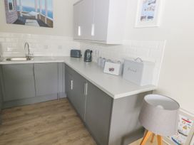 A kitchen with grey cabinets white countertop a sink a toaster kettle and kitchen canisters at 29 Coedrath Park in Saundersfoot