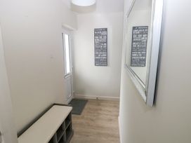 A small entryway with a bench and storage cubbies a wall mirror and a decorative wall sign at 29 Coedrath Park Saundersfoot
