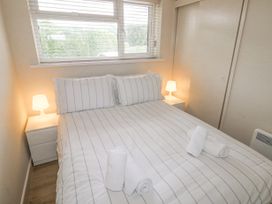A bedroom with a double bed striped bedding two bedside tables with lamps and rolled towels on the bed at 29 Coedrath Park in Saundersfoot