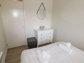 A bedroom with a white dresser a round mirror and a bed with rolled towels at 29 Coedrath Park Saundersfoot