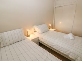 A bedroom with two single beds two bedside tables with lamps and a built in wardrobe at 29 Coedrath Park in Saundersfoot