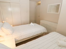 A bedroom with two single beds with striped bedding a dresser a mirror and a closet at 29 Coedrath Park in Saundersfoot