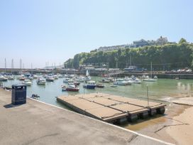 A harbor with many boats docked and a floating platform near a concrete shore at 29 Coedrath Park in Saundersfoot