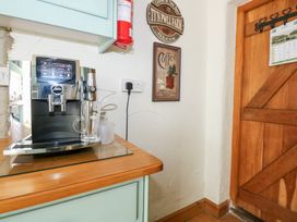 A coffee machine on a wooden countertop next to a wooden door with wall decorations at Ty'n Pwll Farm in Nefyn