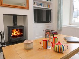 A living room with a fireplace, wooden table, and colorful tea set at Fair View St Just in Roseland near St Mawes
