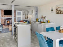 A kitchen and dining area with blue chairs and a fireplace in the background at The Cubby Hole in Sennen Cove