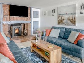 A living room with blue sofas a wooden coffee table a fireplace and a mounted TV at The Cubby Hole in Sennen Cove