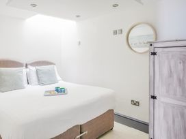 A bedroom with a double bed with pillows and a tray on top a round mirror and a wooden cabinet on the wall at The Cubby Hole in Sennen Cove