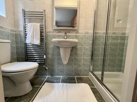 A bathroom with a toilet, towel rack with towel, pedestal sink, mirror, shower with glass doors and bath mat at Penpraze in Portreath