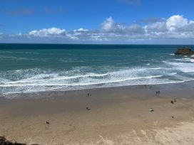 A beach with people near the water and waves at Penpraze in Portreath