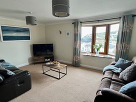A living room with two sofas a coffee table a television and a window with curtains at Curnows in Portreath