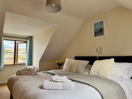 A bedroom with a double bed pillows folded towels window and flowers at Curnows in Portreath