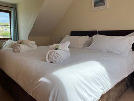 A bedroom with a double bed white pillows and rolled towels near a window with curtains at Curnows Portreath