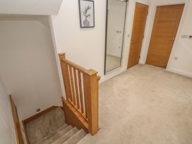 A hallway with a staircase and a mirror at Carnon Gwel, Devoran