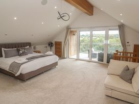A bedroom with a bed and large windows at Carnon Gwel, Devoran