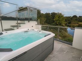 A hot tub on a terrace with stairs and a river view at Carnon Gwel, Devoran