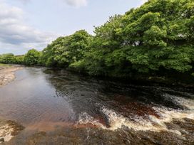 A river with trees along the bank and cloudy sky at Doonalton House in Dromore West, County Sligo