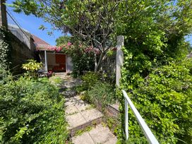 A garden pathway with greenery and a building at The Elbow in Frampton