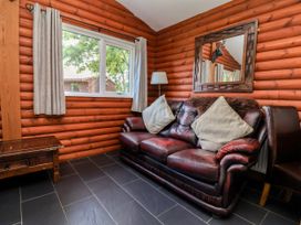 A living room with a leather sofa and window at The Red in Llanerch Park near St Asaph