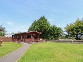 An outdoor view of a log cabin with grass and trees at The Fallows near Llanerch Park near St Asaph