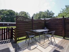 An outdoor patio with a table and chairs at The Fallows in Llanerch Park near St Asaph