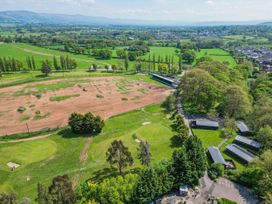 An aerial view of a golf practice range with grassy fields and trees at The Roe in Llanerch Park near St Asaph