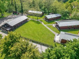 An aerial view of lodges with green lawns and trees at The Roe in Llanerch Park near St Asaph