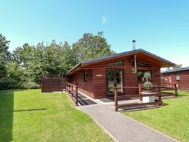 A log cabin with a pathway and grassy area at The Roe Llanerch Park near St Asaph