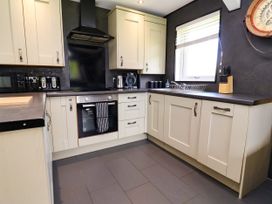A kitchen with cabinets, oven, sink, and kettle at The Roe in Llanerch Park near St Asaph