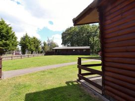 A log cabin with greenery and pathway at The Roe in Llanerch Park near St Asaph