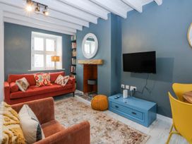 A living room with a sofa and bookshelf at East meets West Criccieth