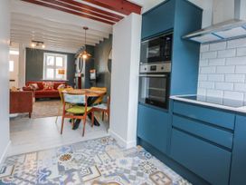 A kitchen with cabinets and a dining table at East meets West Criccieth
