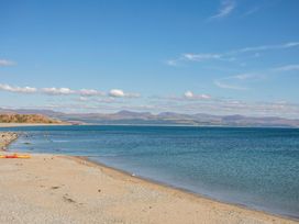 A beach with water and mountains in the background at East meets West Criccieth
