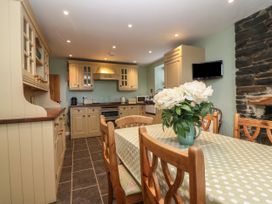 A kitchen with wooden cabinets a dining table with a polka dot tablecloth and a vase of flowers at Priddbwll in Llansannan