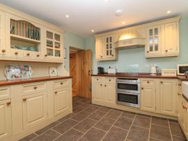 A kitchen with cream cabinets a wooden door oven and various kitchen appliances at Priddbwll in Llansannan