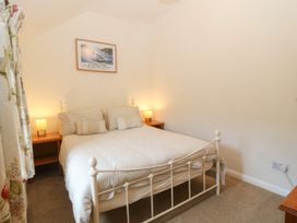 A bedroom with a double bed flanked by two bedside tables with lamps and a framed picture on the wall at Priddbwll in Llansannan