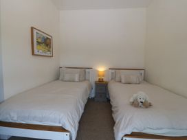 A bedroom with two single beds a nightstand with a lamp and a framed picture on the wall at Priddbwll Llansannan